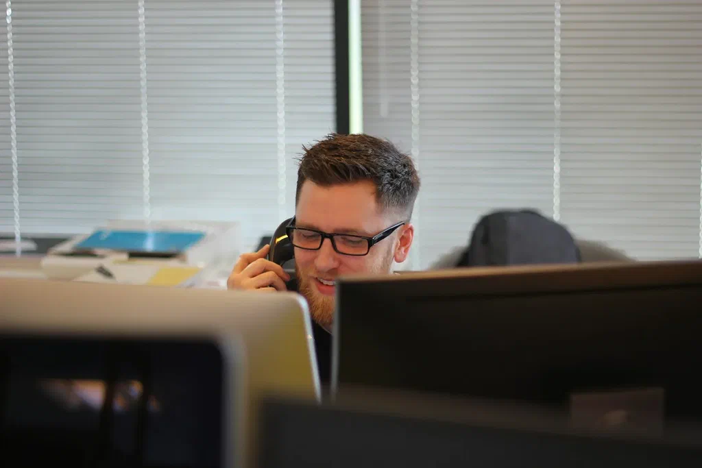 Man in glasses taking a phone call at his desk